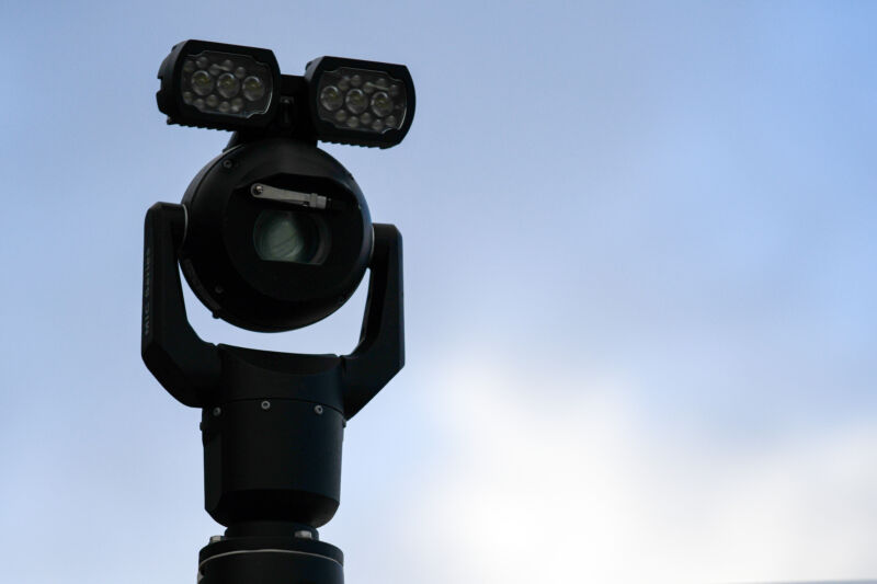 Vaguely menacing camera atop an outdoor metal post.